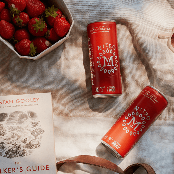 Mockapolitan can placed on a cozy picnic blanket next to fresh strawberries and a book.