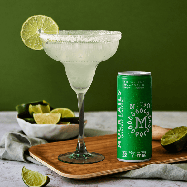 Non-alcoholic cocktail Mockarita poured into a salted margarita glass with lime garnish—Nitro Mocktails citrus mocktail with orange and lime.