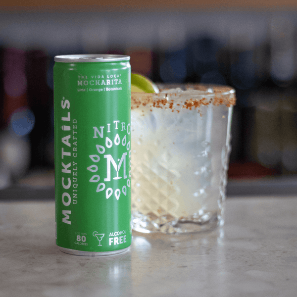 Nitro Mocktails Mockarita can beside a tajin-rimmed margarita glass with lime wedge—refreshing non-alcoholic margarita alternative.