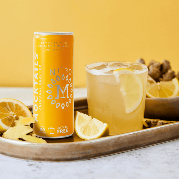 Mockscow Mule non-alcoholic cocktail on tray with lemon wedges and ginger root beside a chilled can—alcohol-free, non-carbonated ginger lemon mocktail.