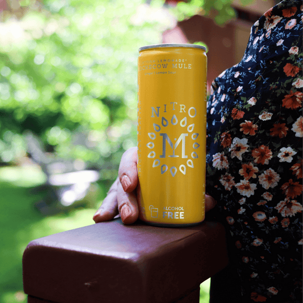 Person holding a can of Nitro Mocktails Mockscow Mule non-alcoholic cocktail outdoors—alcohol-free Moscow Mule with bold ginger and lemon sour flavor.