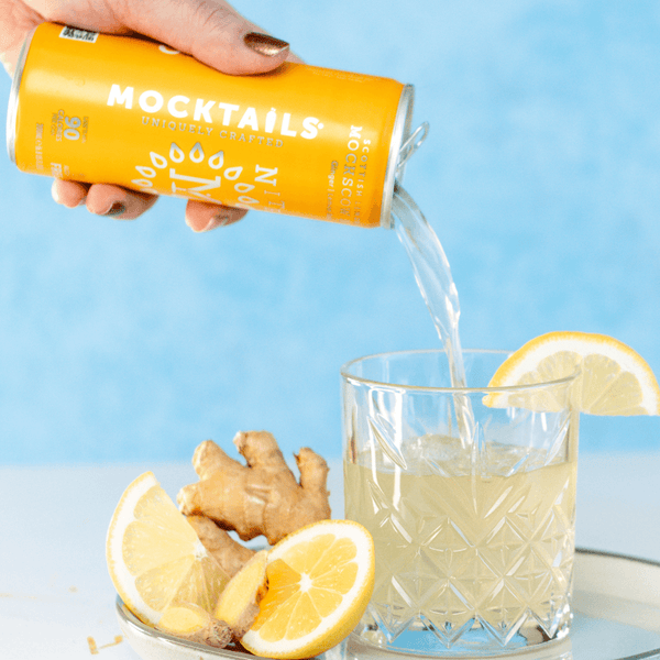 Hand pouring Mockscow Mule into a rocks glass over lemon slices and ginger root—nitro-infused, non-alcoholic cocktail Moscow Mule.