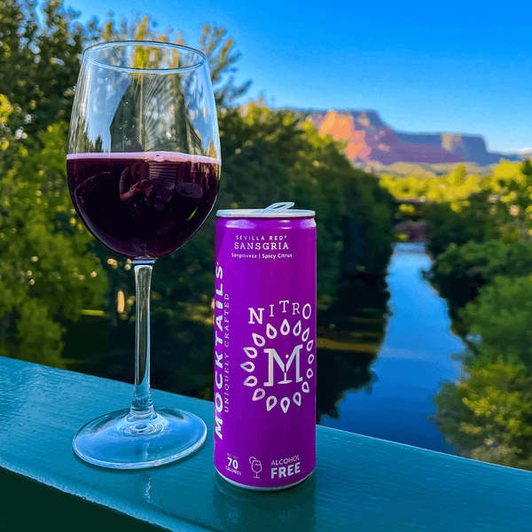 Can of Nitro Mocktails Sansgria and glass of non-alcoholic sangria cocktail on scenic overlook, ideal for sober sipping and alcohol-free enjoyment.