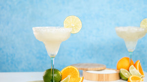 Classic non-alcoholic margarita made with Nitro Mocktails Mockarita, served in a salt rimmed margarita glass on a blue background