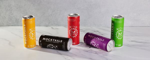 Five colorful Nitro Mocktails cans on a light gray surface with a neutral background